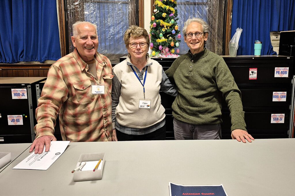 Three volunteers smile in the mail service area